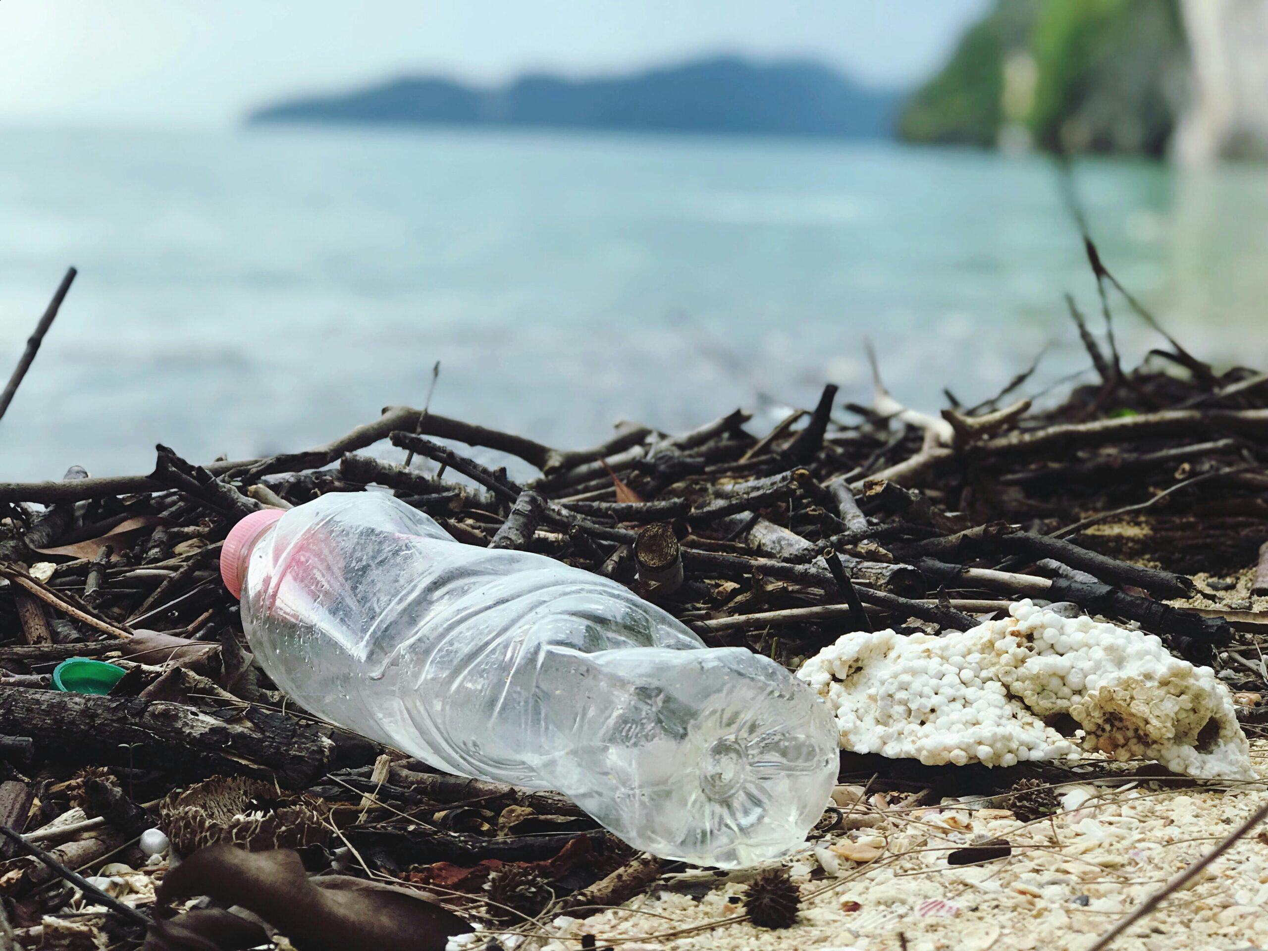 Garrafa plástica descartada em uma praia da Malásia, destacando a poluição ambiental.